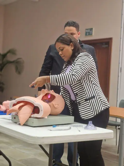 Instructora explica un procedimiento sobre un simulador anatómico de torso