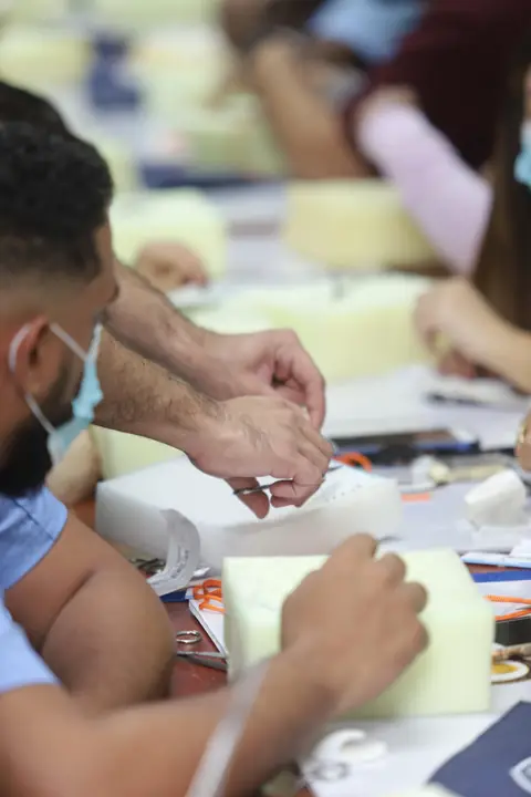 Manos de participantes practicando suturas en almohadillas de silicona