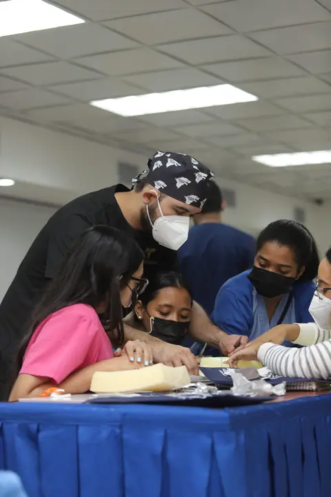 Grupo de participantes practica procedimientos sobre un brazo de simulación