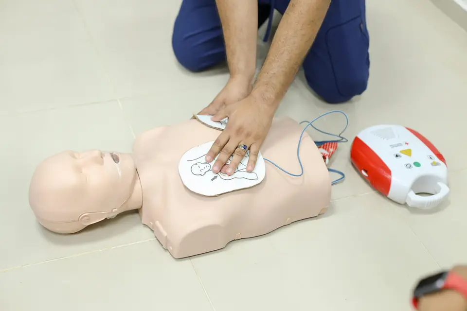 Compresiones torácicas sobre un maniquí con un desfibrilador externo automático al lado