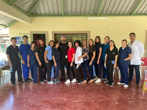 Grupo de egresados con uniforme médico posa en un área exterior