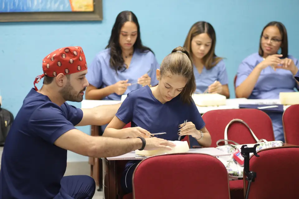 Instructor con gorro quirúrgico enseña técnicas de sutura a un grupo de participantes