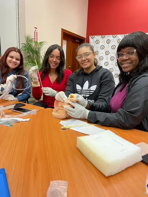 Participantes sonríen mientras practican con simuladores en una mesa de taller