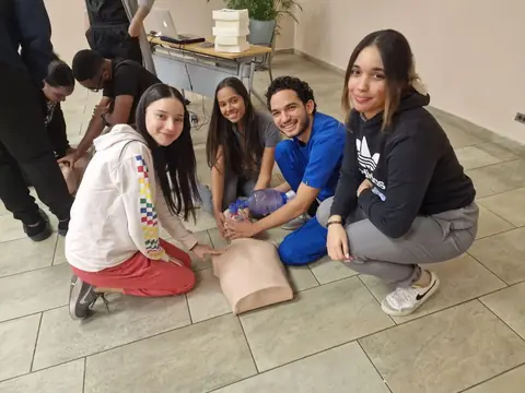 Participantes practican reanimación cardiopulmonar en el suelo con maniquíes