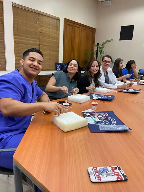 Participantes en un taller práctico de suturas alrededor de una mesa