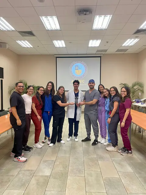 Grupo de egresados con uniforme médico posa en el salón de clases