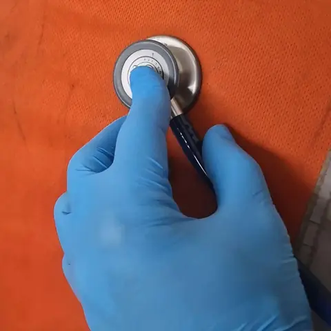 Mano con guante sostiene la campana de un estetoscopio