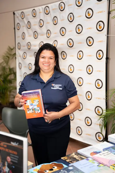 Expositora muestra un libro en el área de patrocinadores