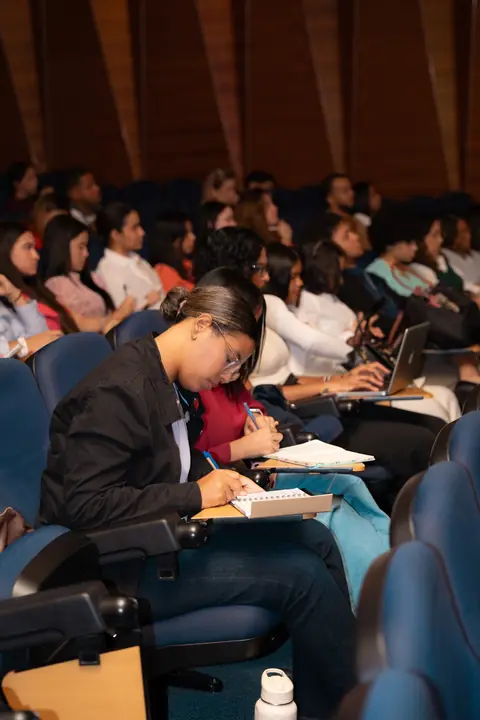 Asistente toma notas durante una conferencia en el auditorio