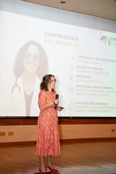 Ponente con micrófono frente a su presentación en pantalla