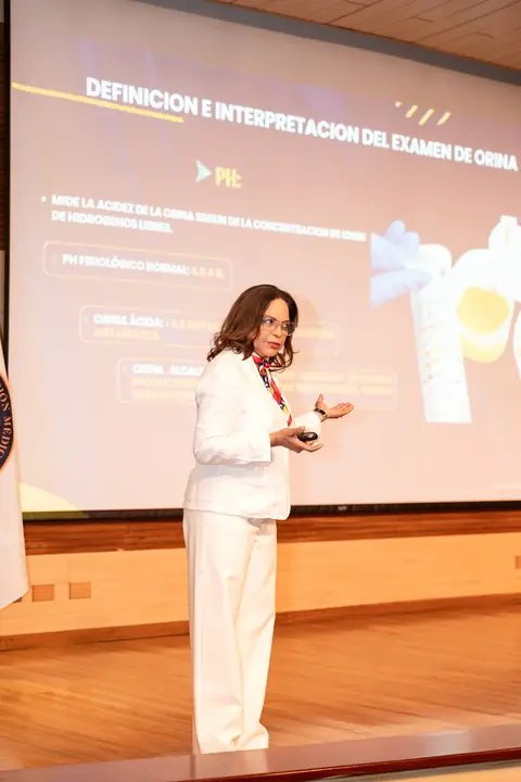 Ponente explica la interpretación del examen de orina frente a la pantalla del auditorio