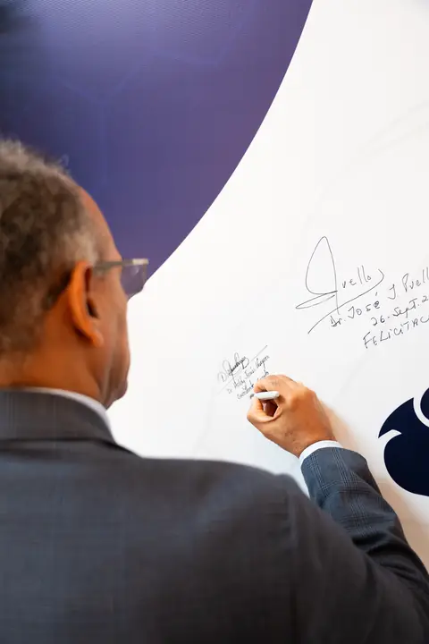 Invitado firma el mural de firmas del evento